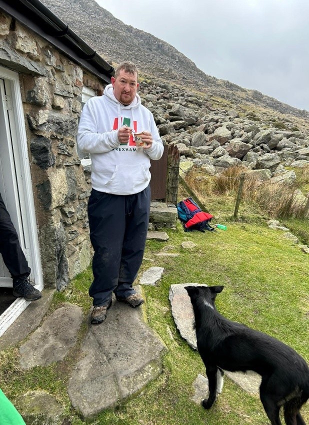 Geraint on mountain drinking hot drink with a dog