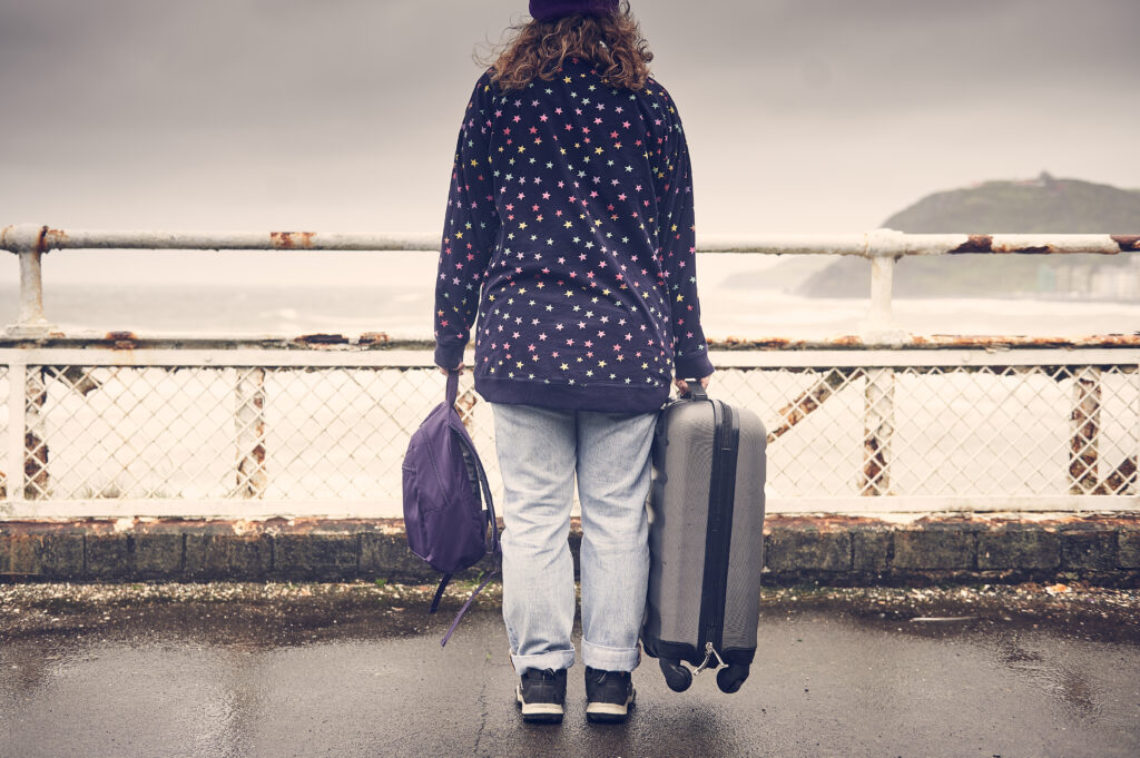 person holding suitcase and rugsack