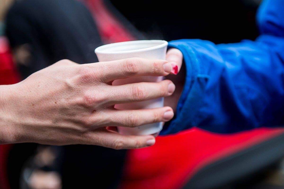 Hands holding a plastic cup of tea