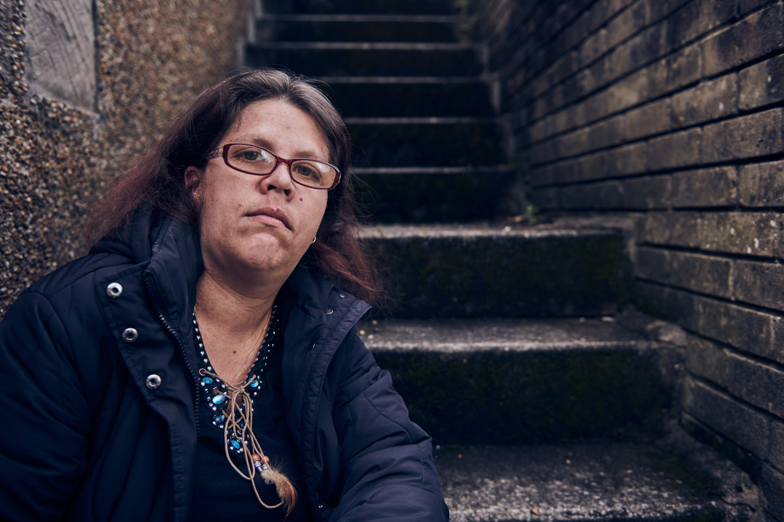 Female service user sat on outdoors stairs at homeless project in Bridgend. The Wallich