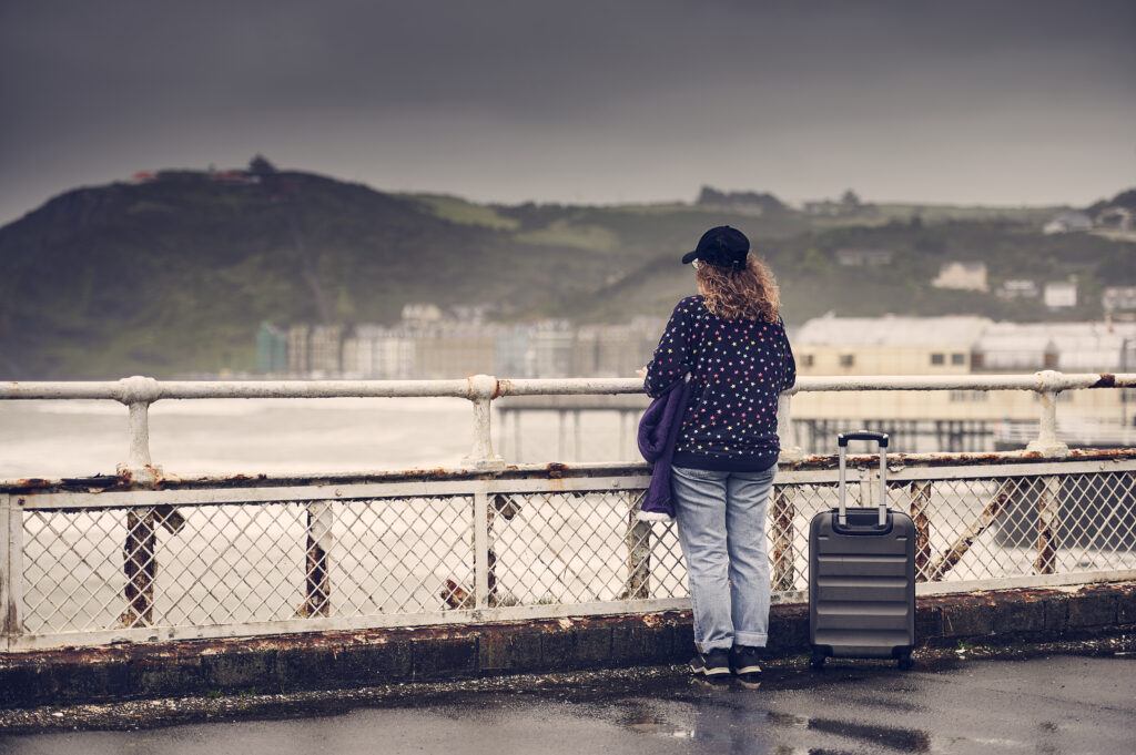 Person with all her possessions staring at the sea