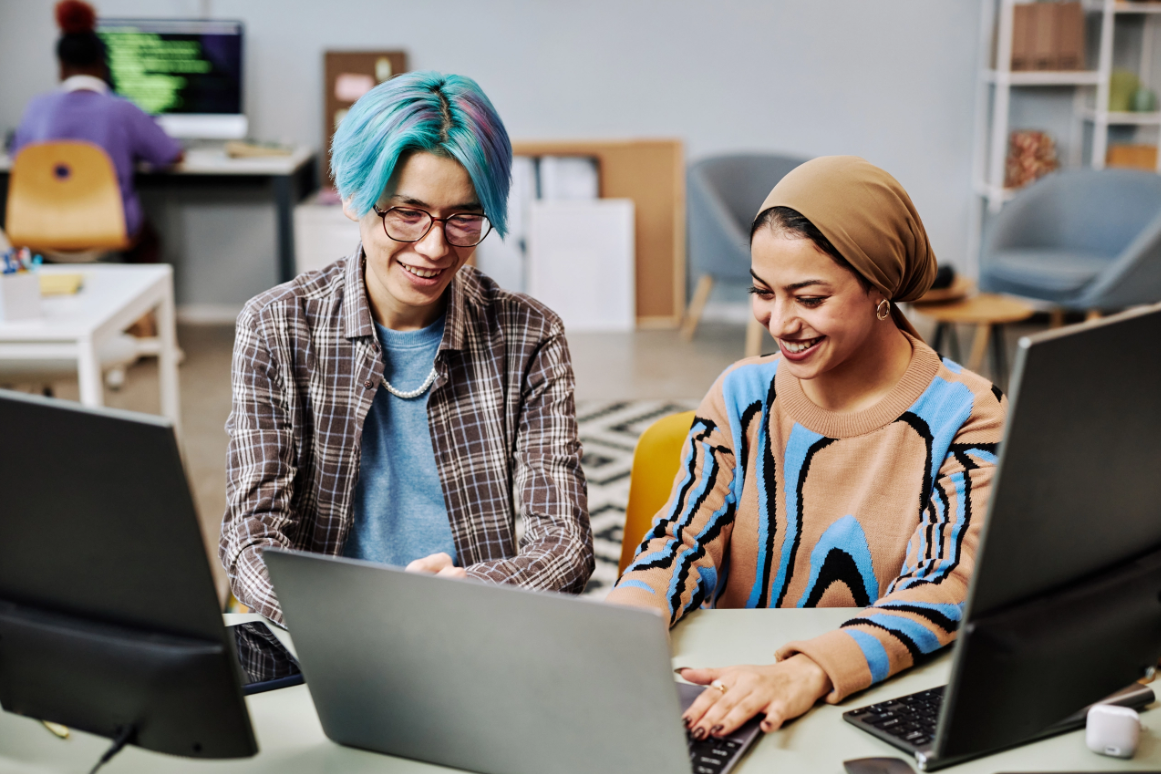 Two people in an office setting, looking at a laptop