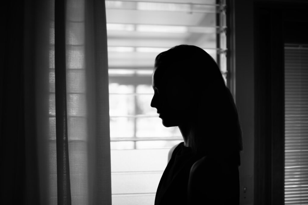 Emotional young female looking out her window.