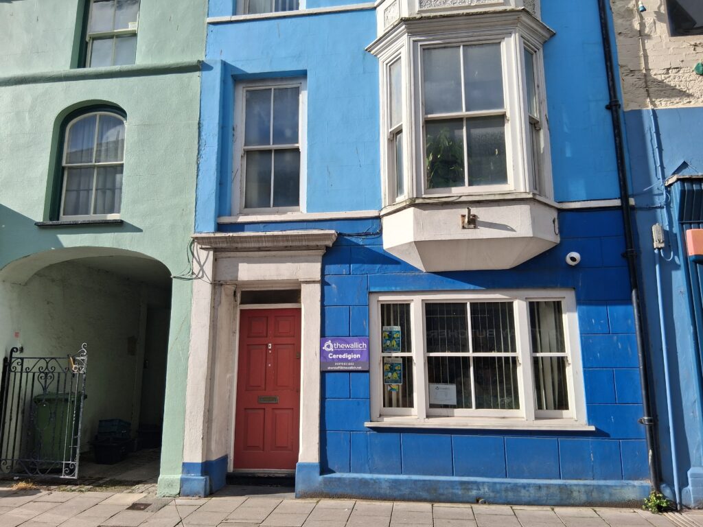A Victorian terraced building painted blue, with white windows