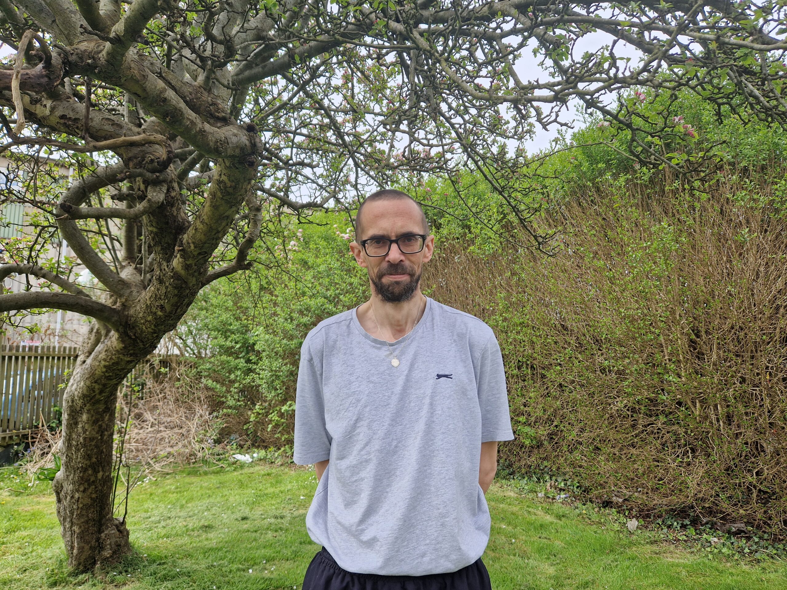 Person in temporary accommodation stood under tree