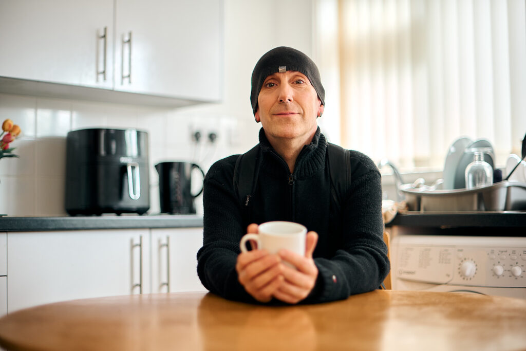 Service user sitting in kitchen with hot drink