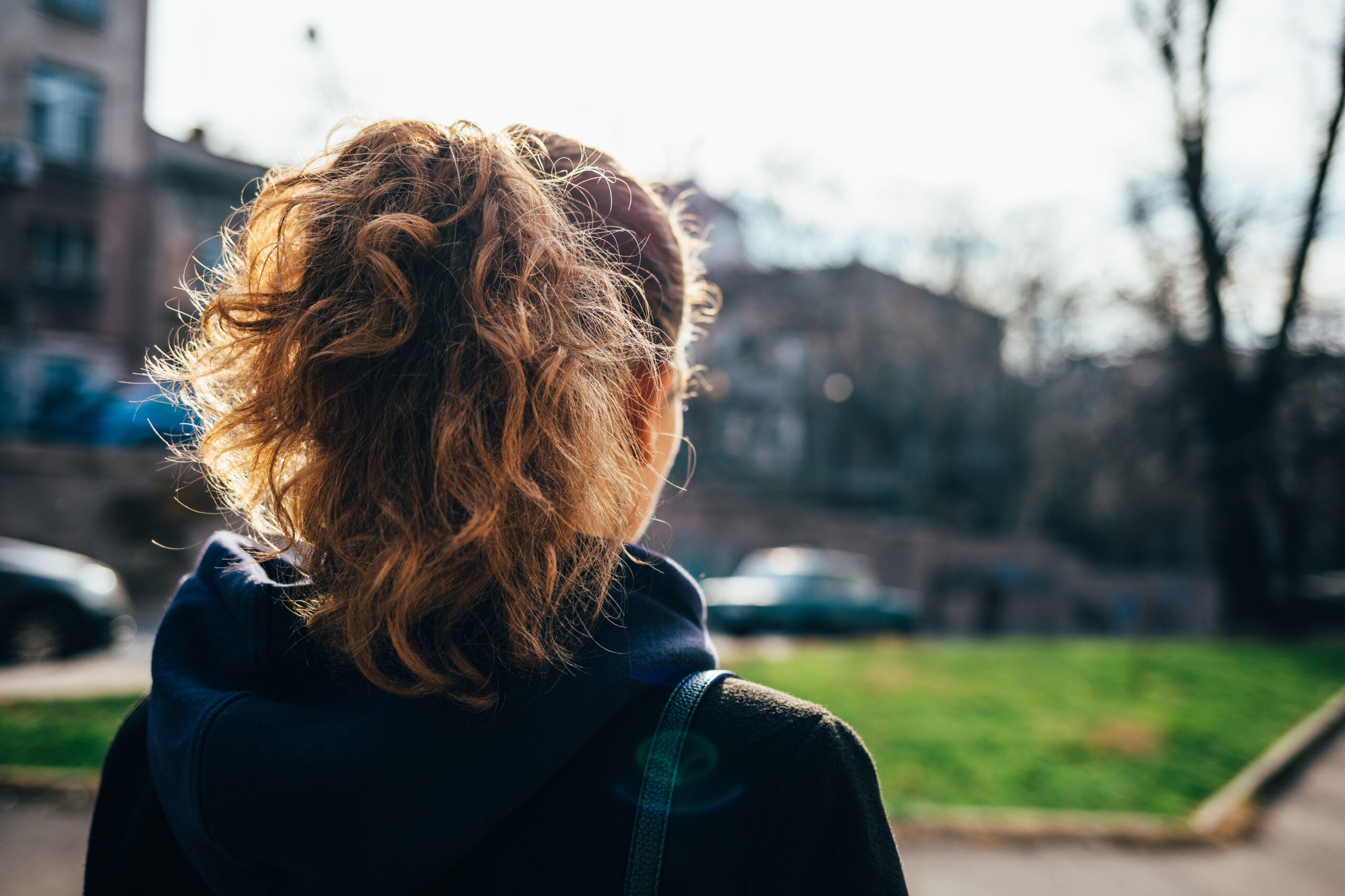 A young woman seen from behind, with a mousy ponytail and wearing a hooded top.